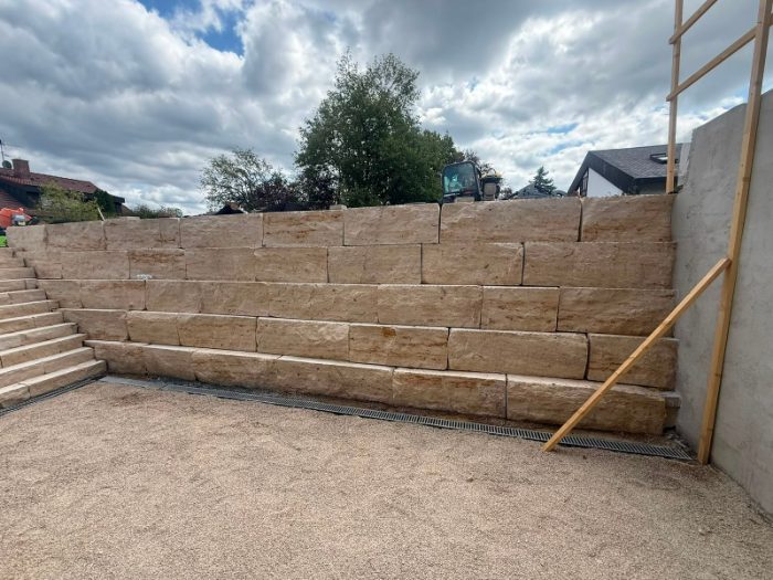 Stützmauer aus Sandstein-Blockstufen mit integrierter Treppe und Entwässerungsrinne