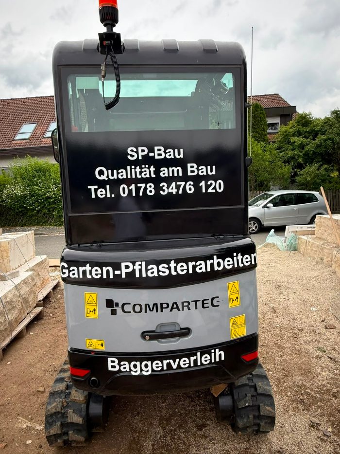 Mini-Bagger von SP BAU mit Firmenbeschriftung – Garten-, Pflasterarbeiten und Baggerverleih