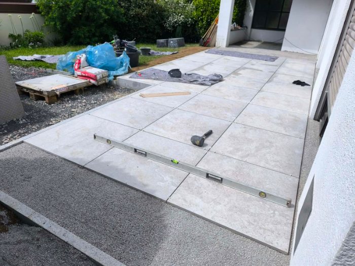 Verlegung großformatiger Feinsteinzeugplatten mit Wasserwaage und Gummihammer
