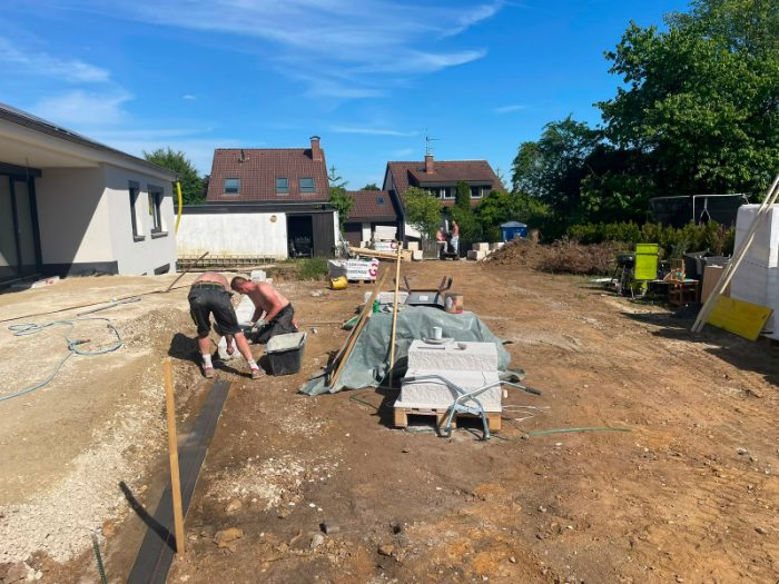 Zwei Mitarbeiter von SP BAU setzen Randsteine auf einer Neubaubaustelle