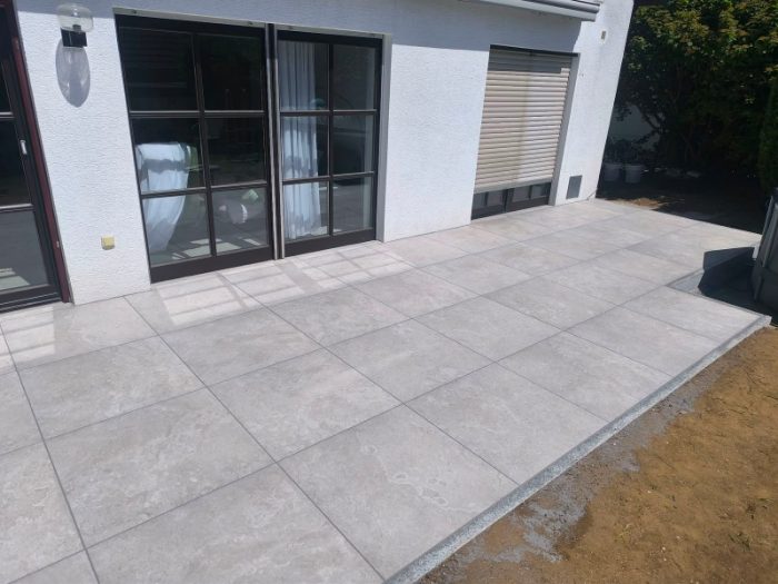 Fertige Terrasse aus grauen Feinsteinzeugplatten mit sauberer Granitrandsteinkante