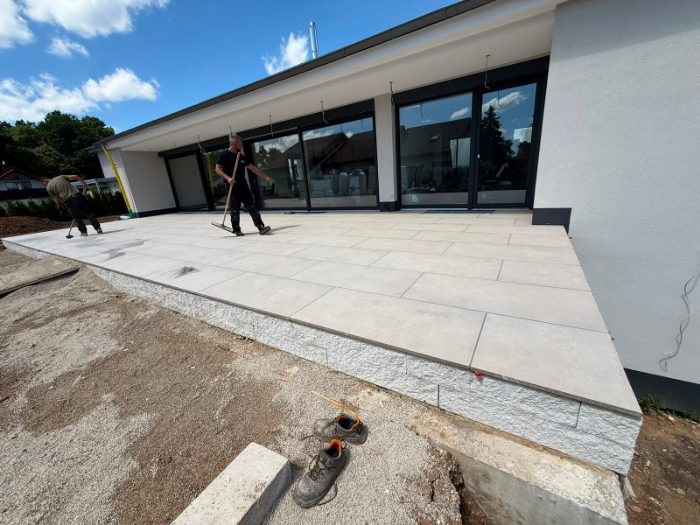 Zwei Mitarbeiter von SP BAU kehren die frisch verlegte Terrasse ab