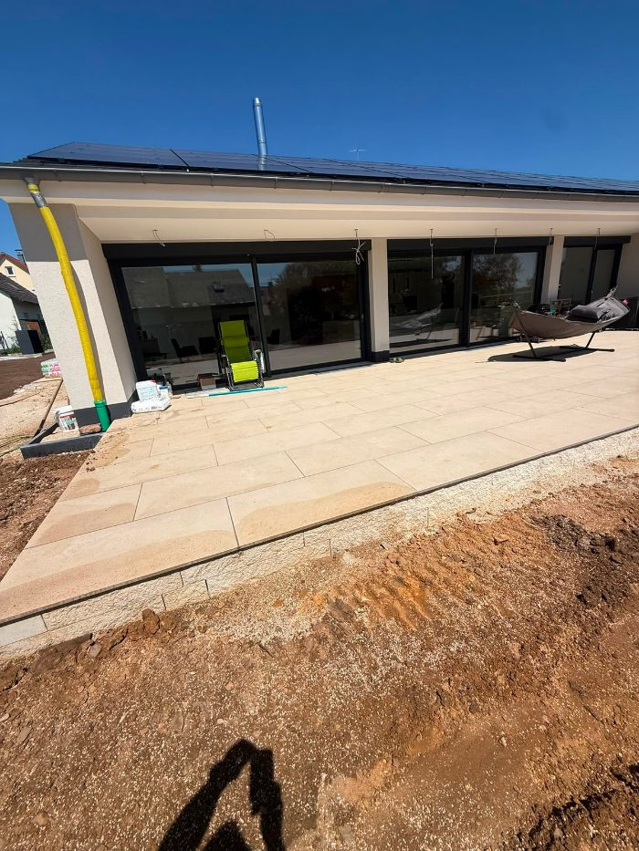 Große Terrasse aus hellen Großformatplatten an einem Bungalow