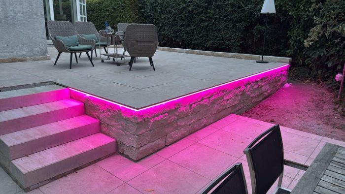 Fertige Terrasse mit Natursteinmauer und indirekter LED-Beleuchtung, davor Blockstufentreppe